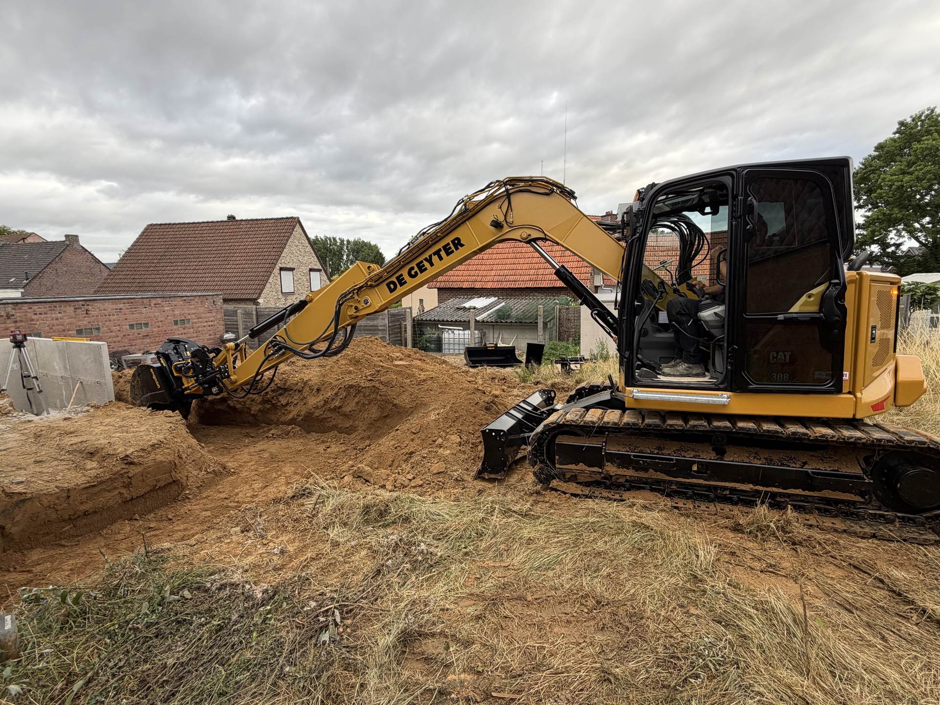 CAT 308 van De Geyter graaft een bouwput uit tussen woningen